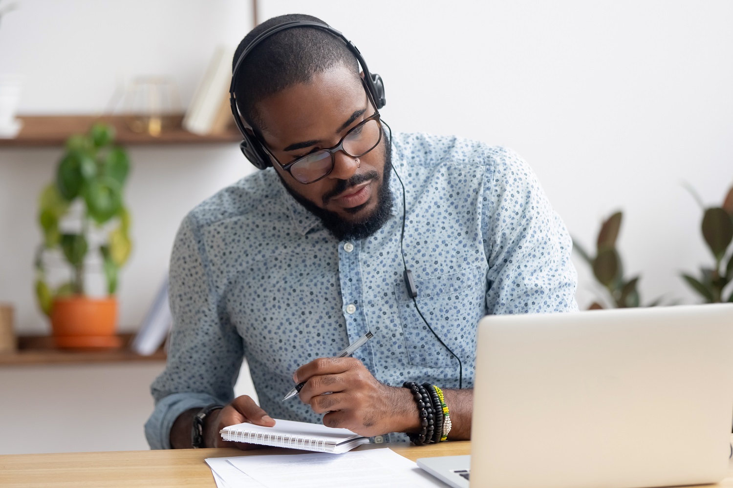 Man with headphones on taking notes